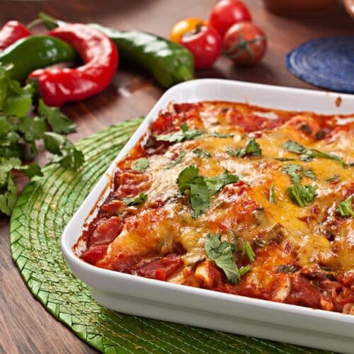 Dish with baked enchiladas topped with herbs.