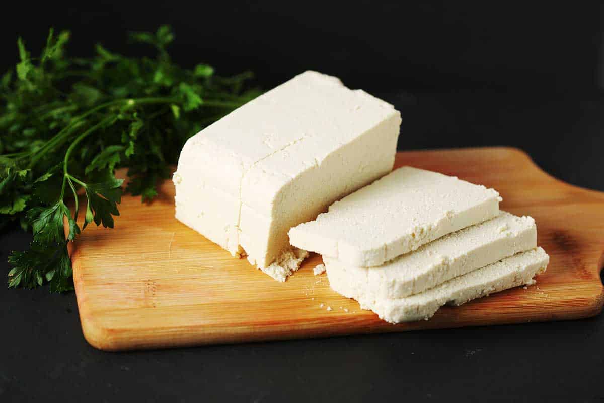 Silken tofu sliced on top of the wooden cutting board. 