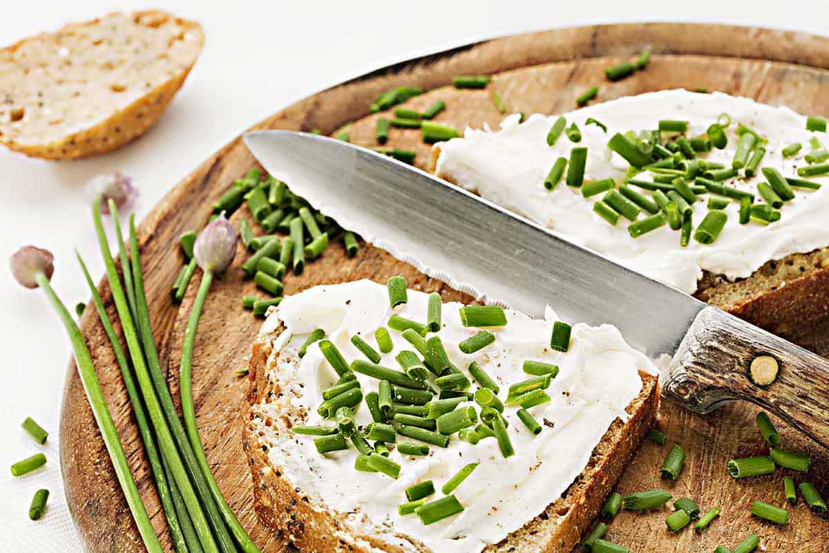 Bread slices topped with cream cheese on the round wooden plate. 