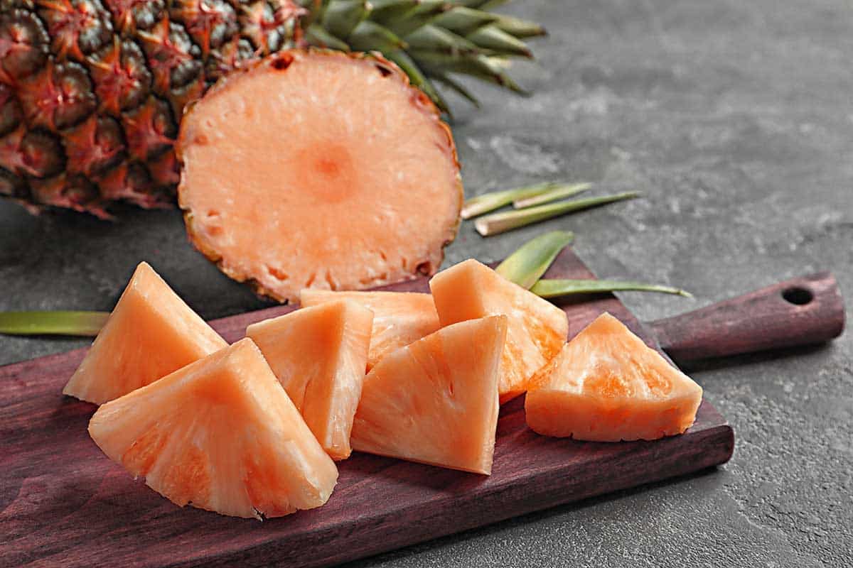 Cutting board with sliced pink pineapple. 