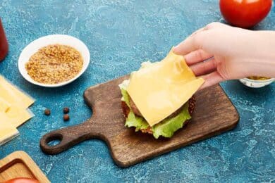 serving board with hamburger topped with American cheese.