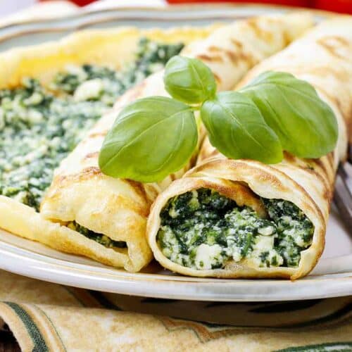 Plate with crepes filled with broccoli and cream.
