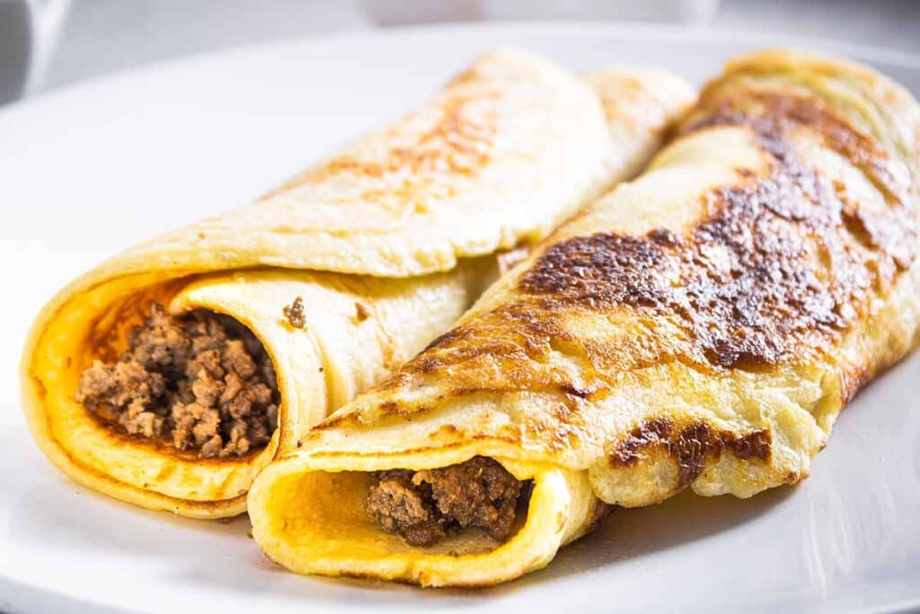Plate with crepes filled with taco meat, close up shot. 