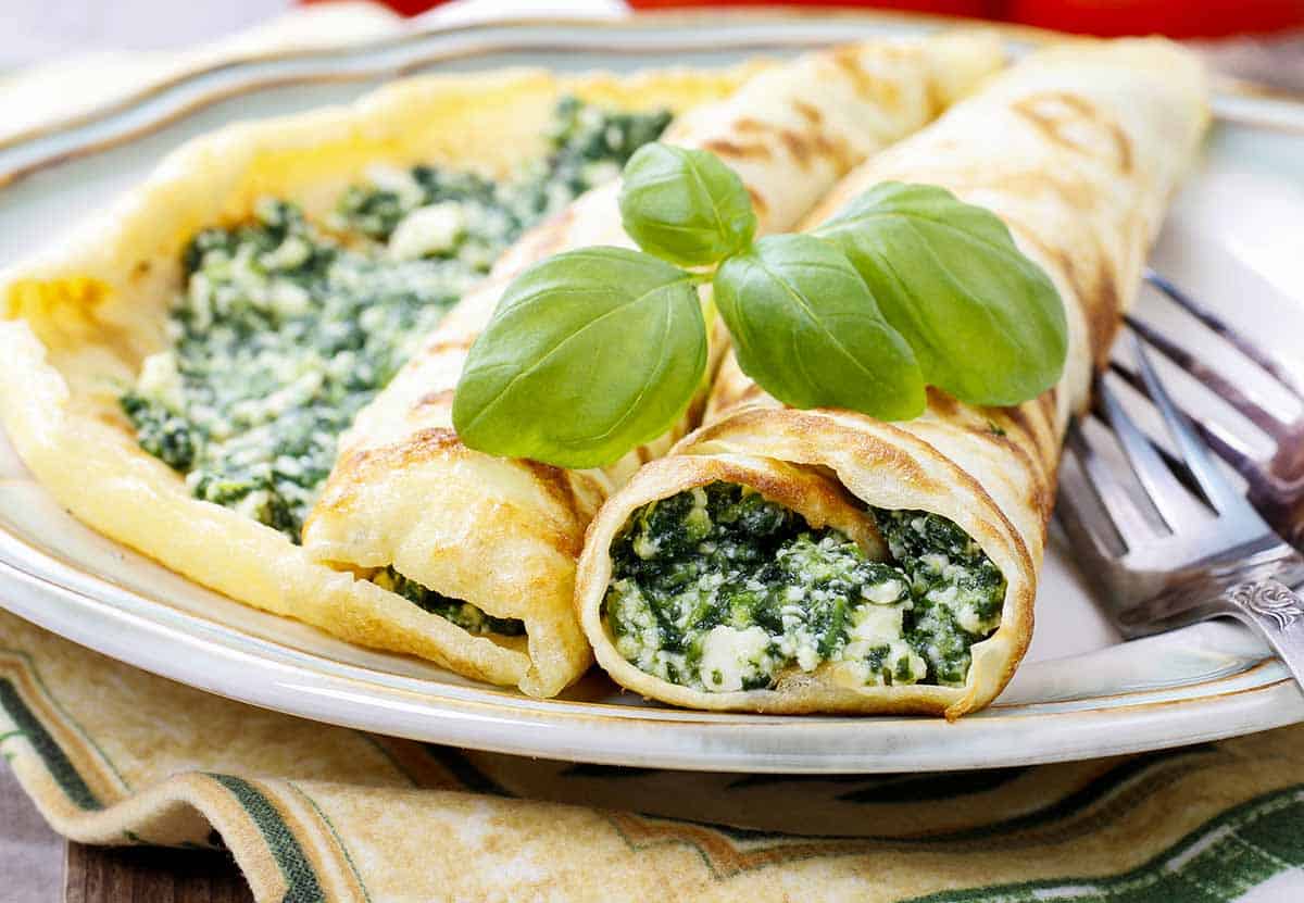 Plate with crepes filled with broccoli and cream. 