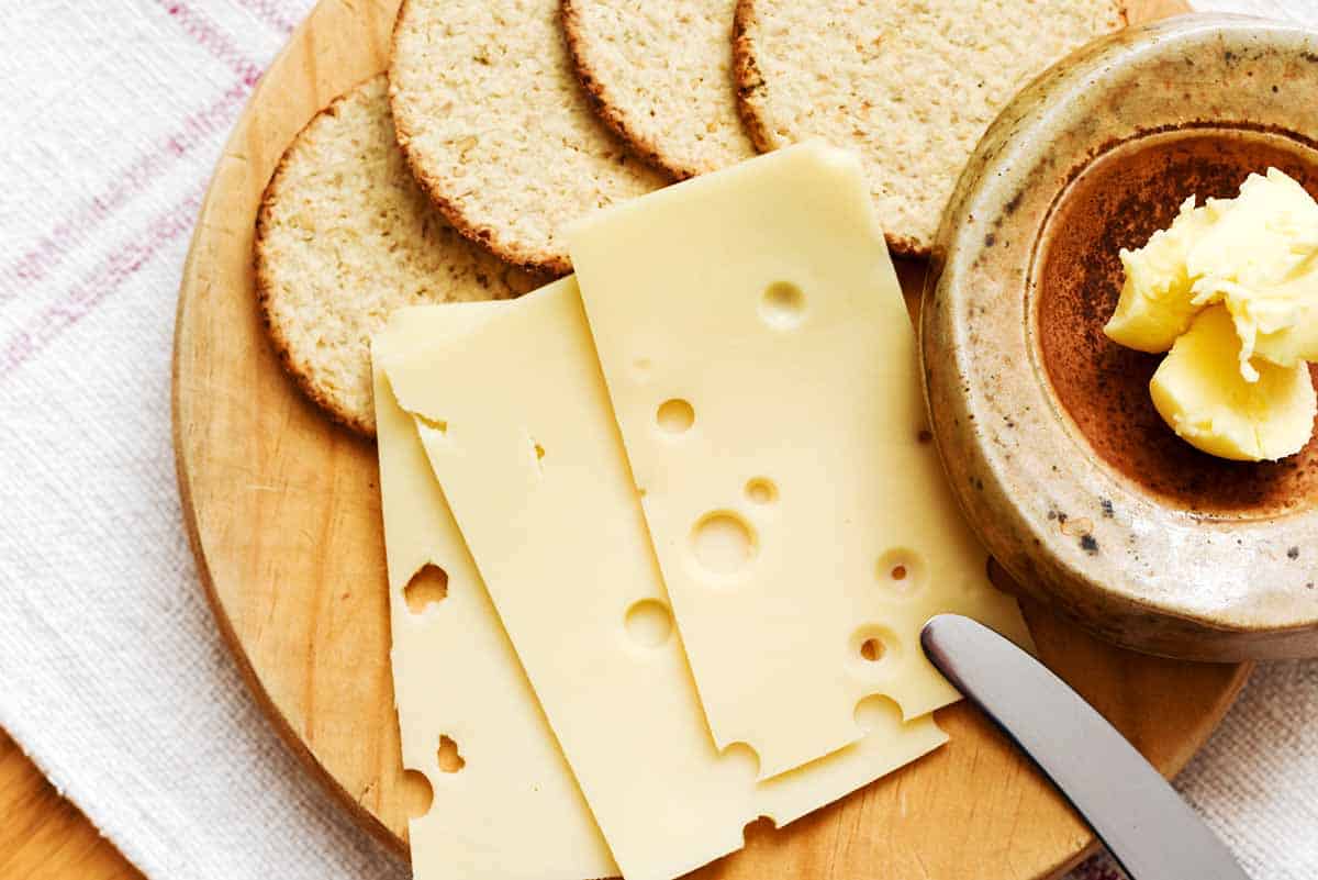 sliced Emmental cheese served with crackers and spread. 