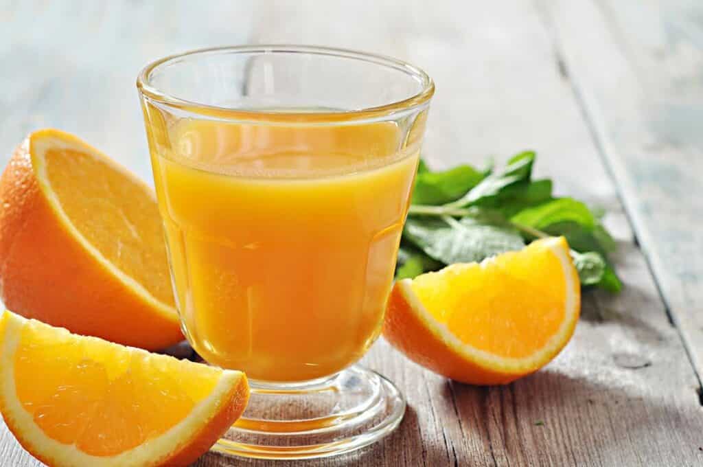 Sliced orange and glass filled with orange juice. 