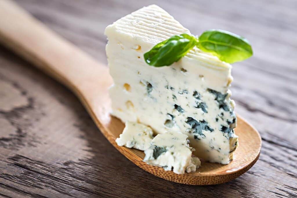 Large spoon with a serving of blue cheese. 