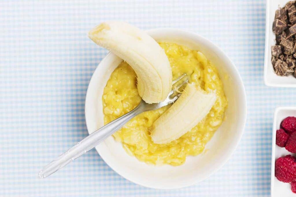Bowl with mashed bananas and the fork. 
