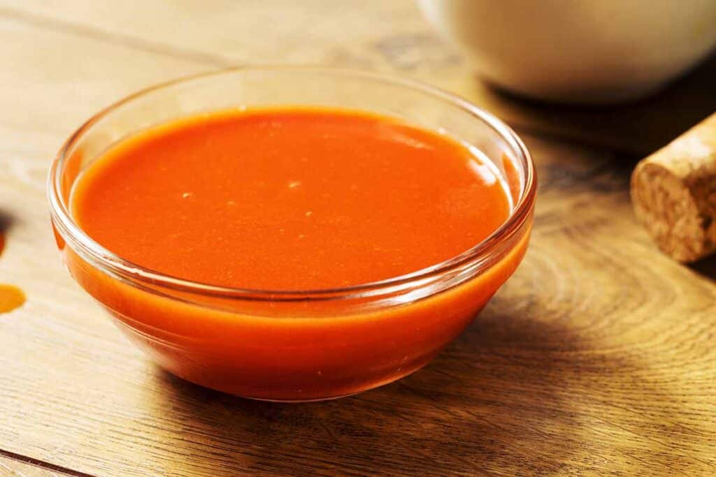 Small bowl filled with tabasco sauce. 