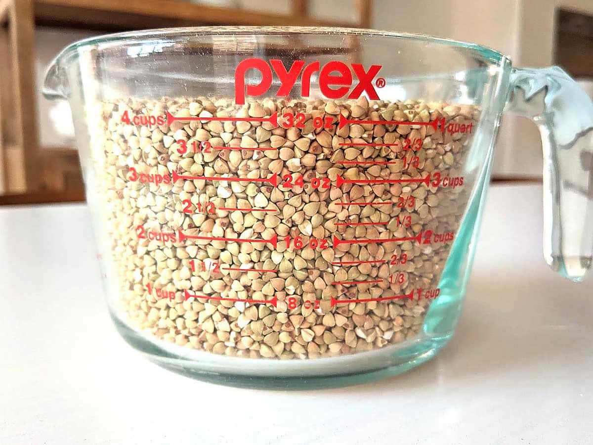 Large Pyrex measuring cup on top of the table with some grains inside. 