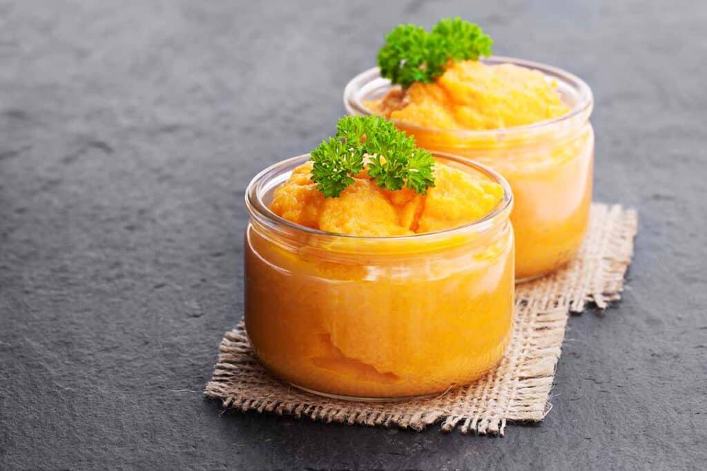Two glass jars filled with carrot puree. 