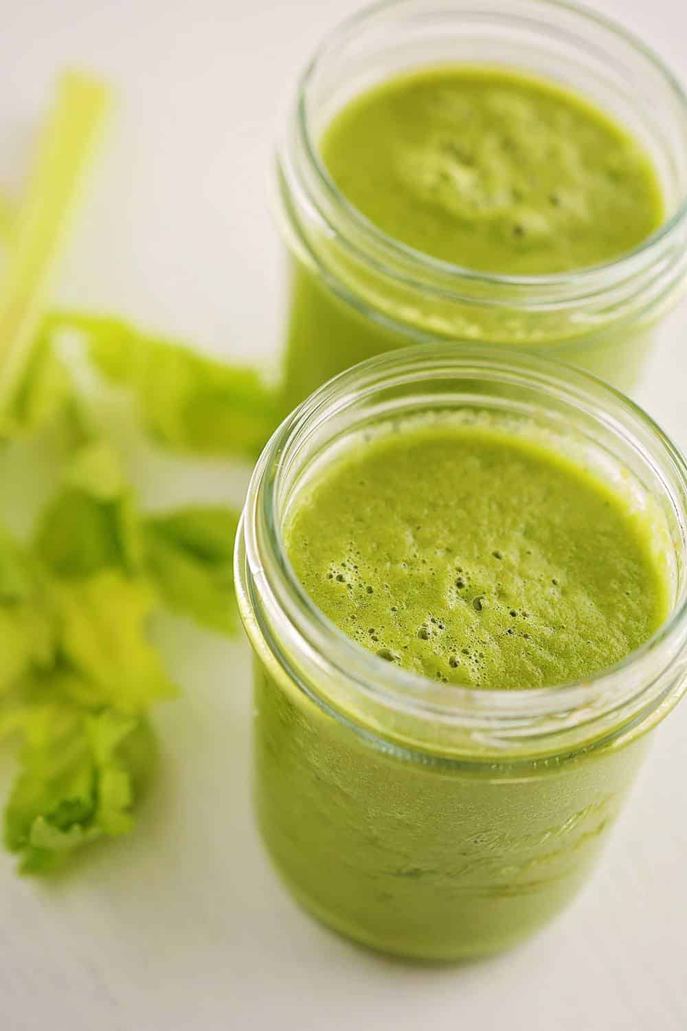 Jar filled with green-colored celery and ginger smoothie. 