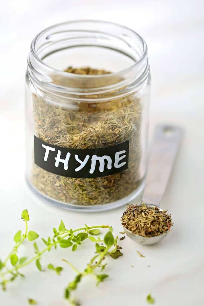 Glass jar filled with dried thyme spice. 