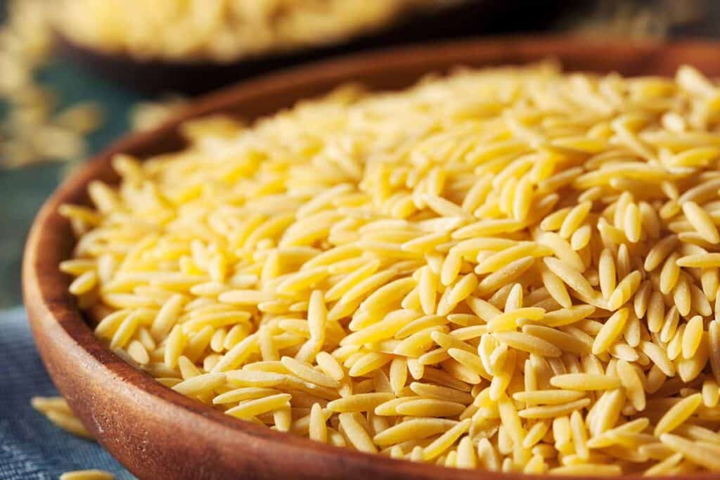 Wooden bowl with dry orzo. 
