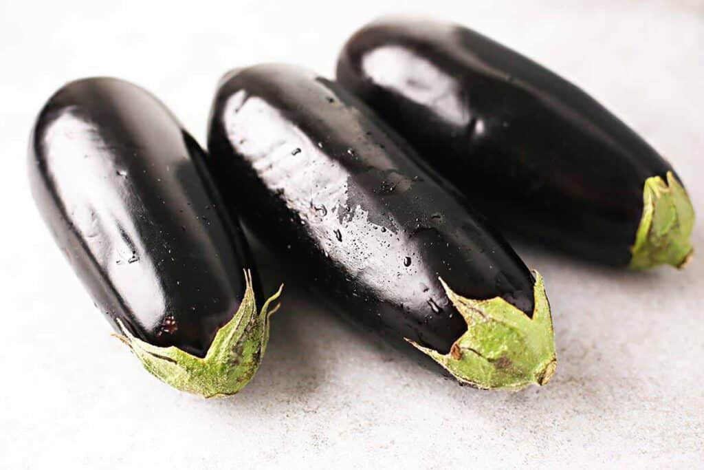 Three whole eggplants on the table. 