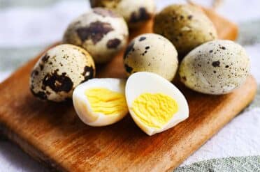Boiled quail eggs on top of the wooden cutting board.
