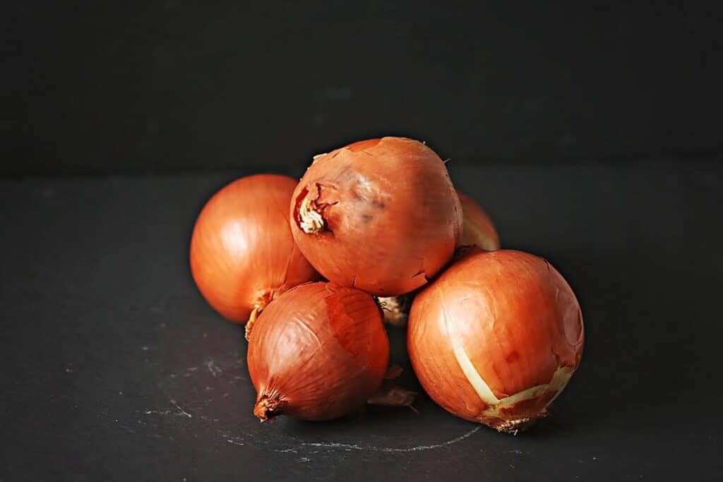 Whole onions on the black backdrop. 