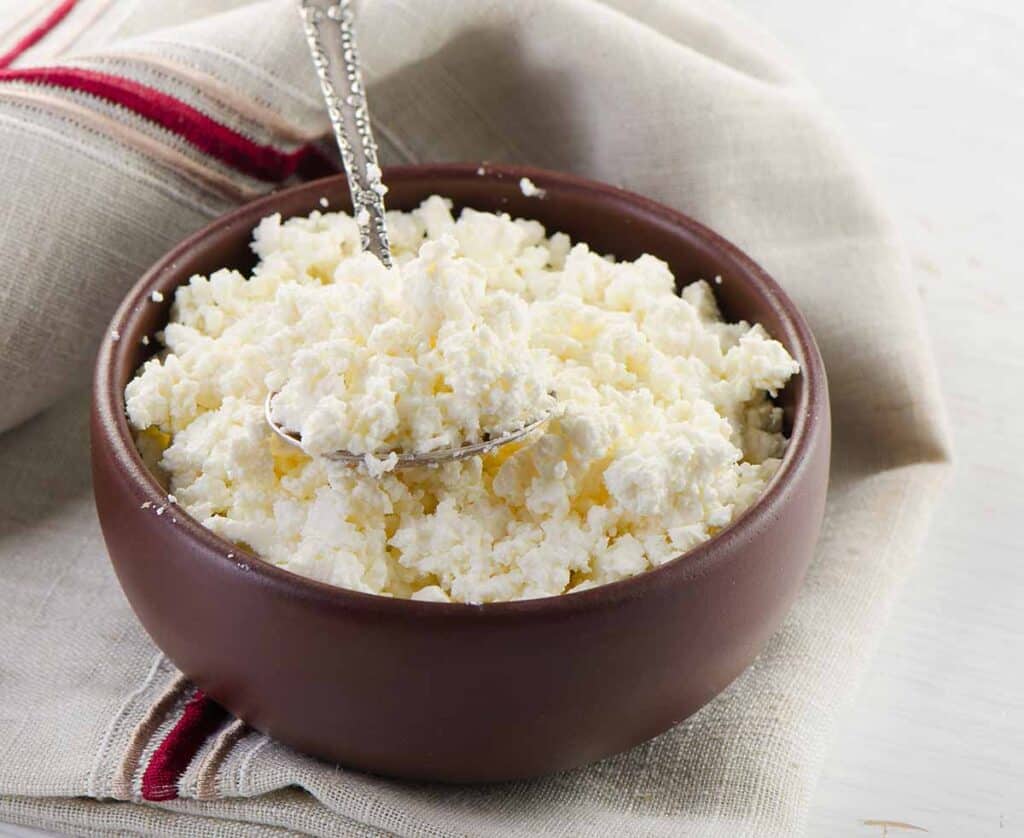 Wooden bowl with cottage cheese and spoon. 