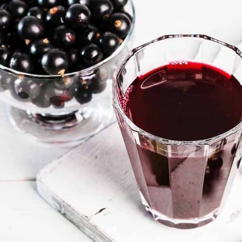 Glass with Elderberry syrup on top of the white background.