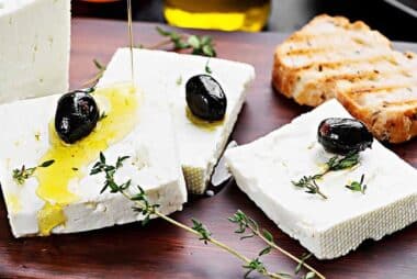 Sliced feta cheese topped with olive oil and black olives.