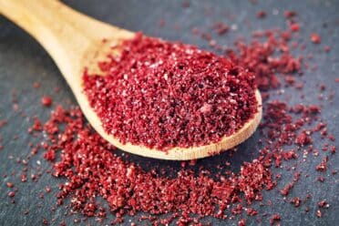 Wooden spoon filled with ground sumac spice.